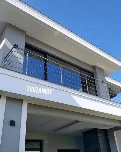 Guarda corpo de aço inox com vidro instalado em sacada com vista para o mar